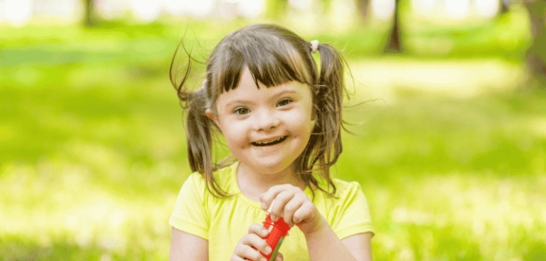 Ein Kind mit Downsyndrom. Sie hat ein gelbes Tshirt