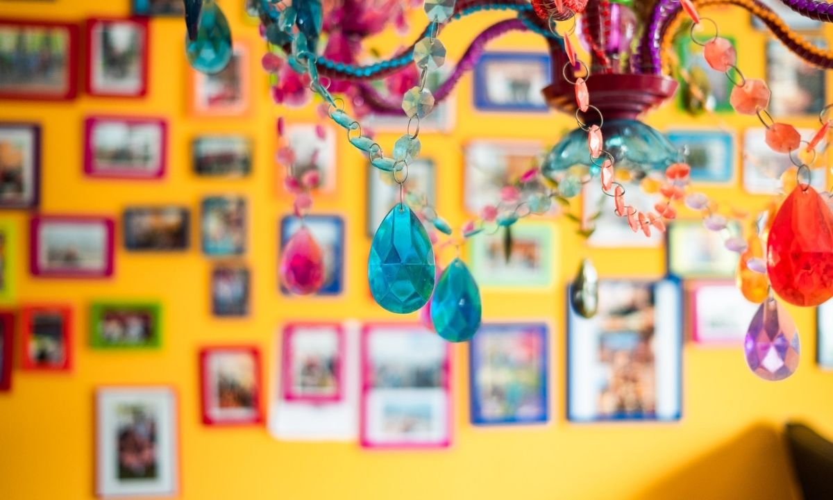 Ein farbenfrohes Bild von einer gelben Wand mit vielen Bilderrahmen aus einer Kinderwohngruppe.