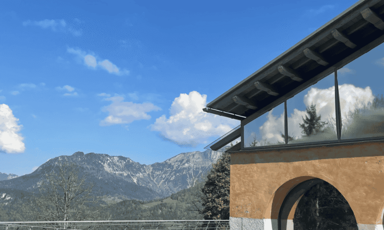 Eine Außenansicht der Dokumentation Obersalzberg, der Himmel spiegelt sich in der Glasfassade.